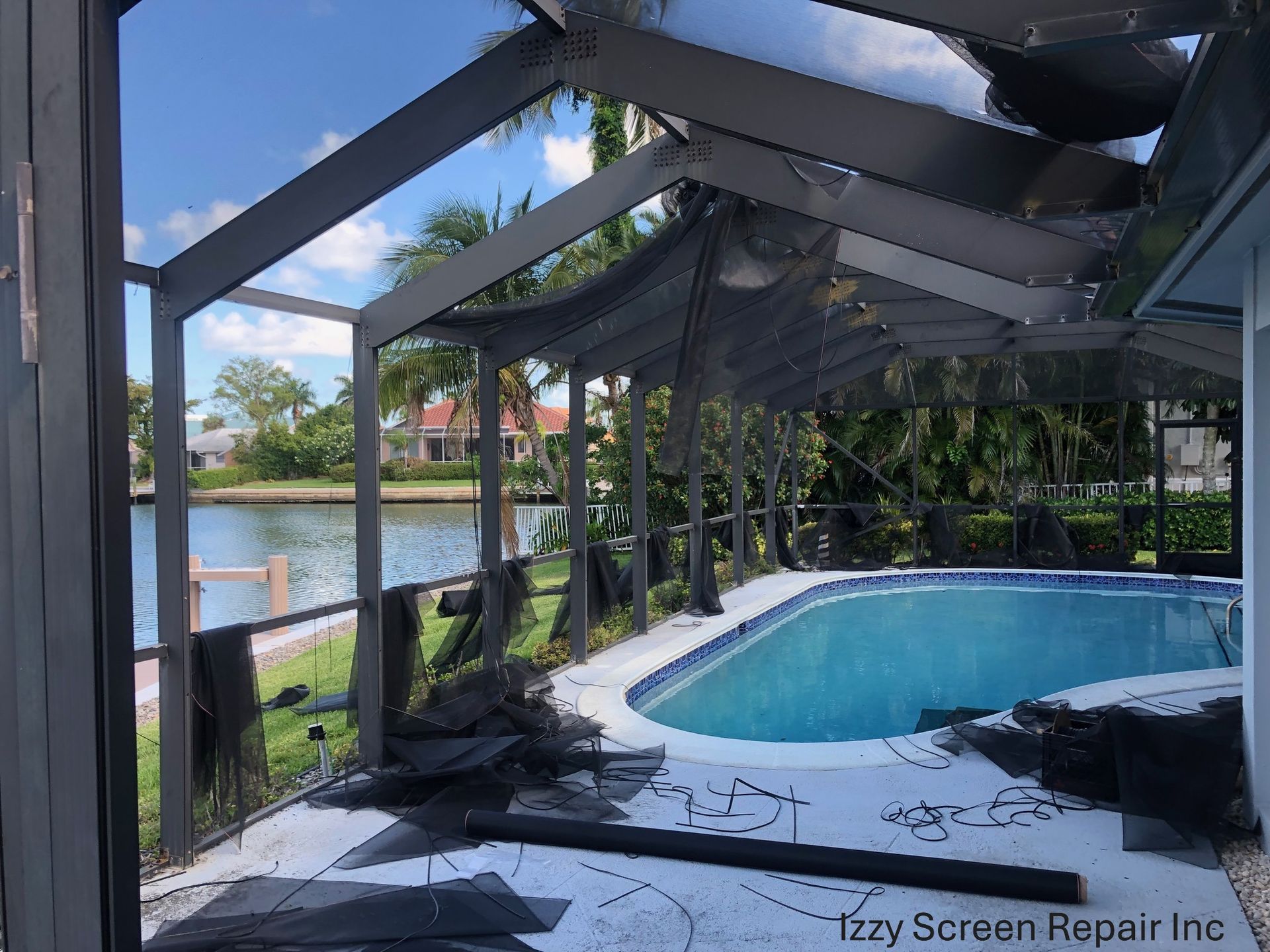 A man is carrying a ladder next to a pool.