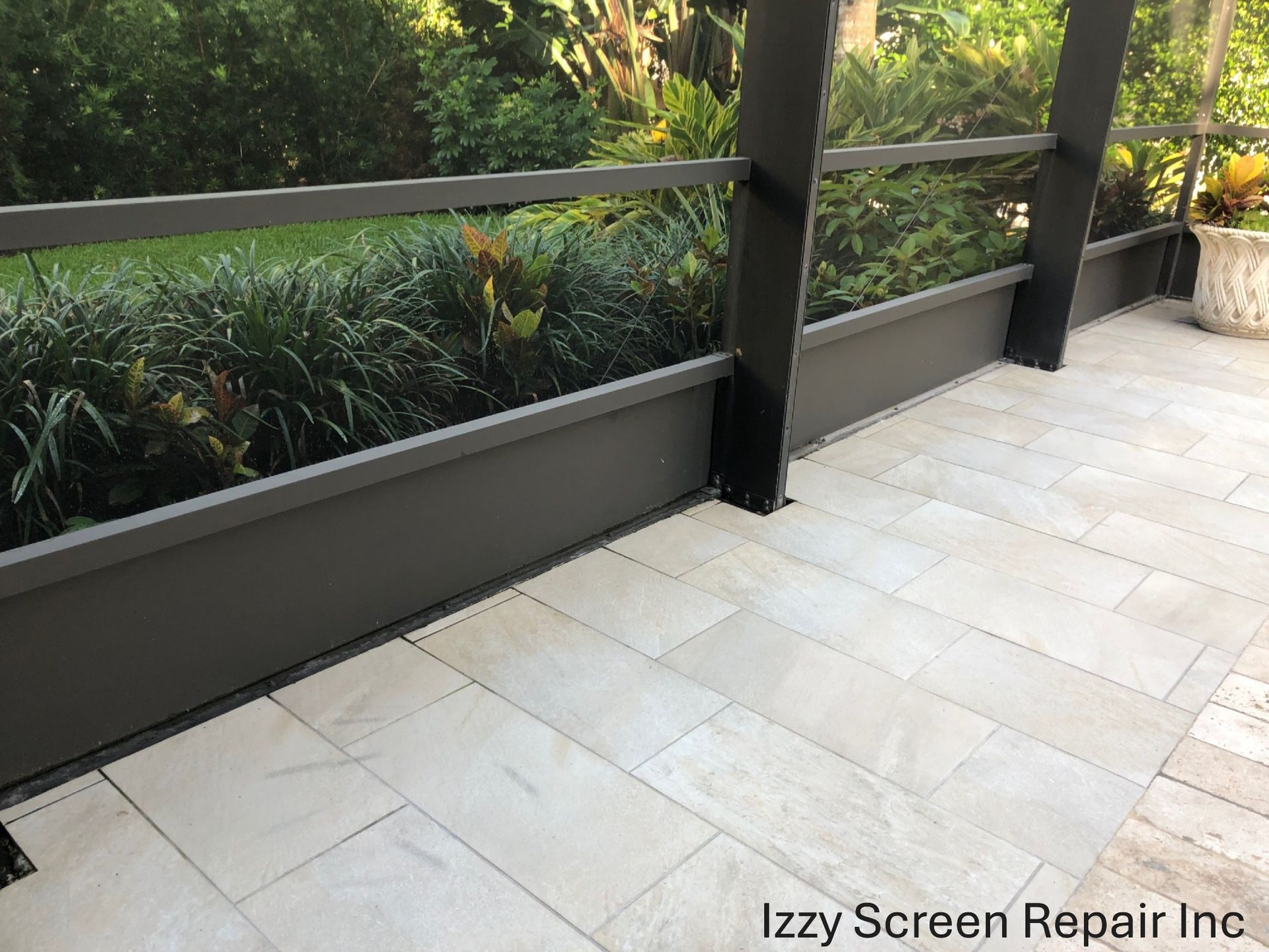 A picture of a screened in porch with the words izzy screen repair inc on the bottom