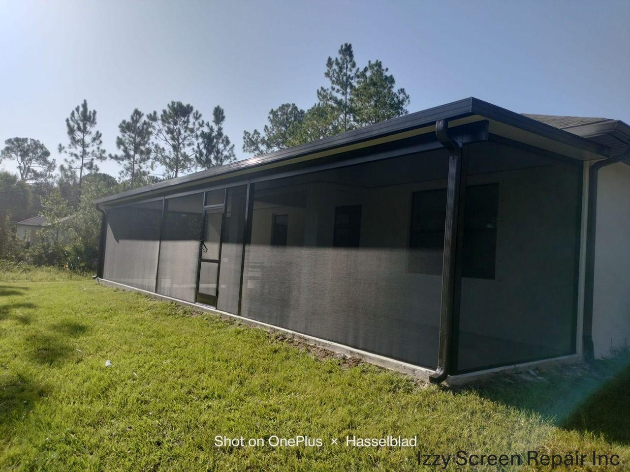 An aerial view of a screened in pool area with a house in the background.