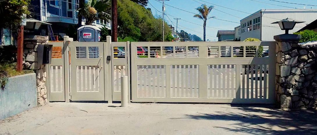 A sliding gate is open to a driveway in front of a house.