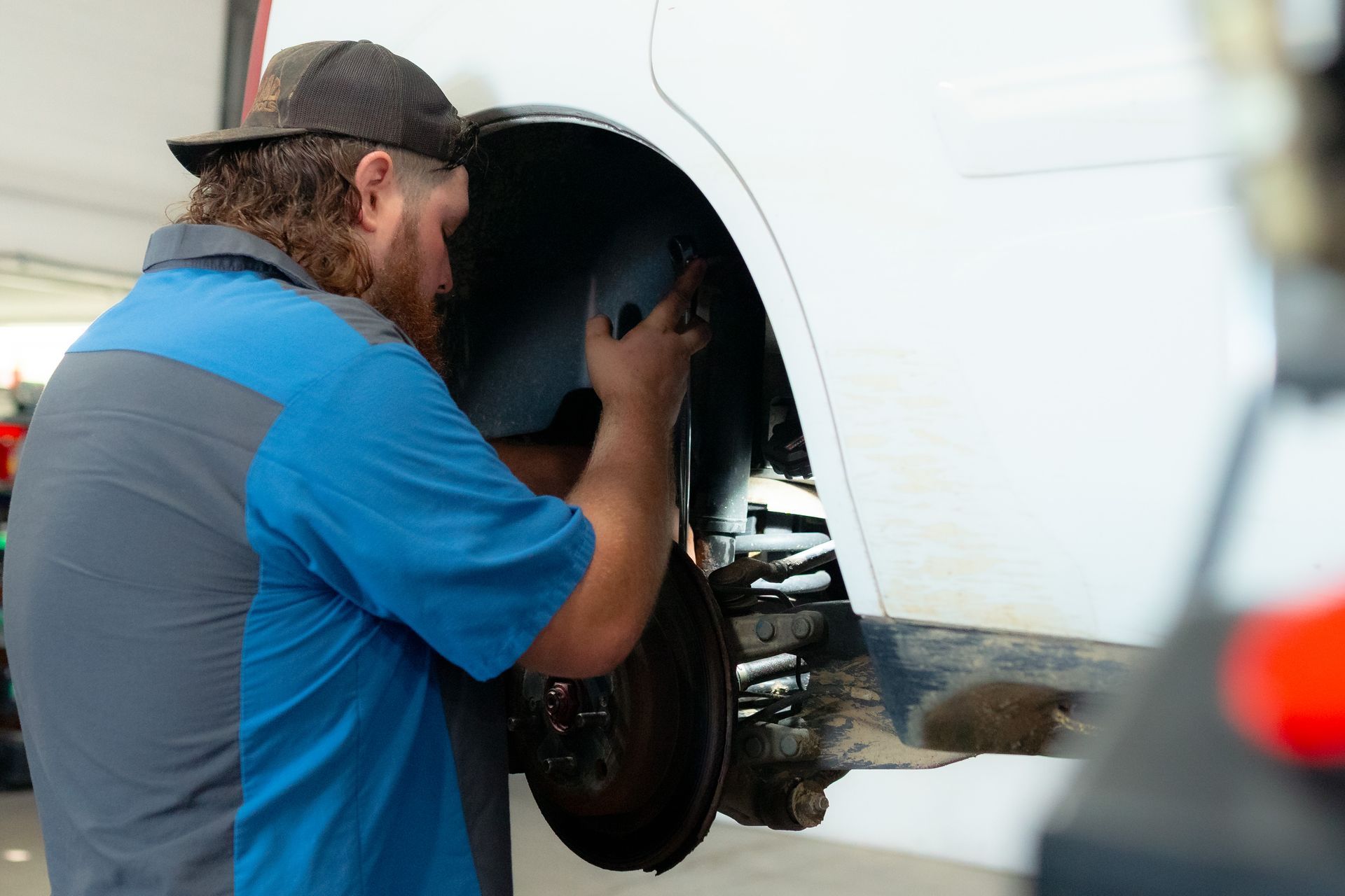 An employee working on a white car replacing the wheel | Huber Automotive