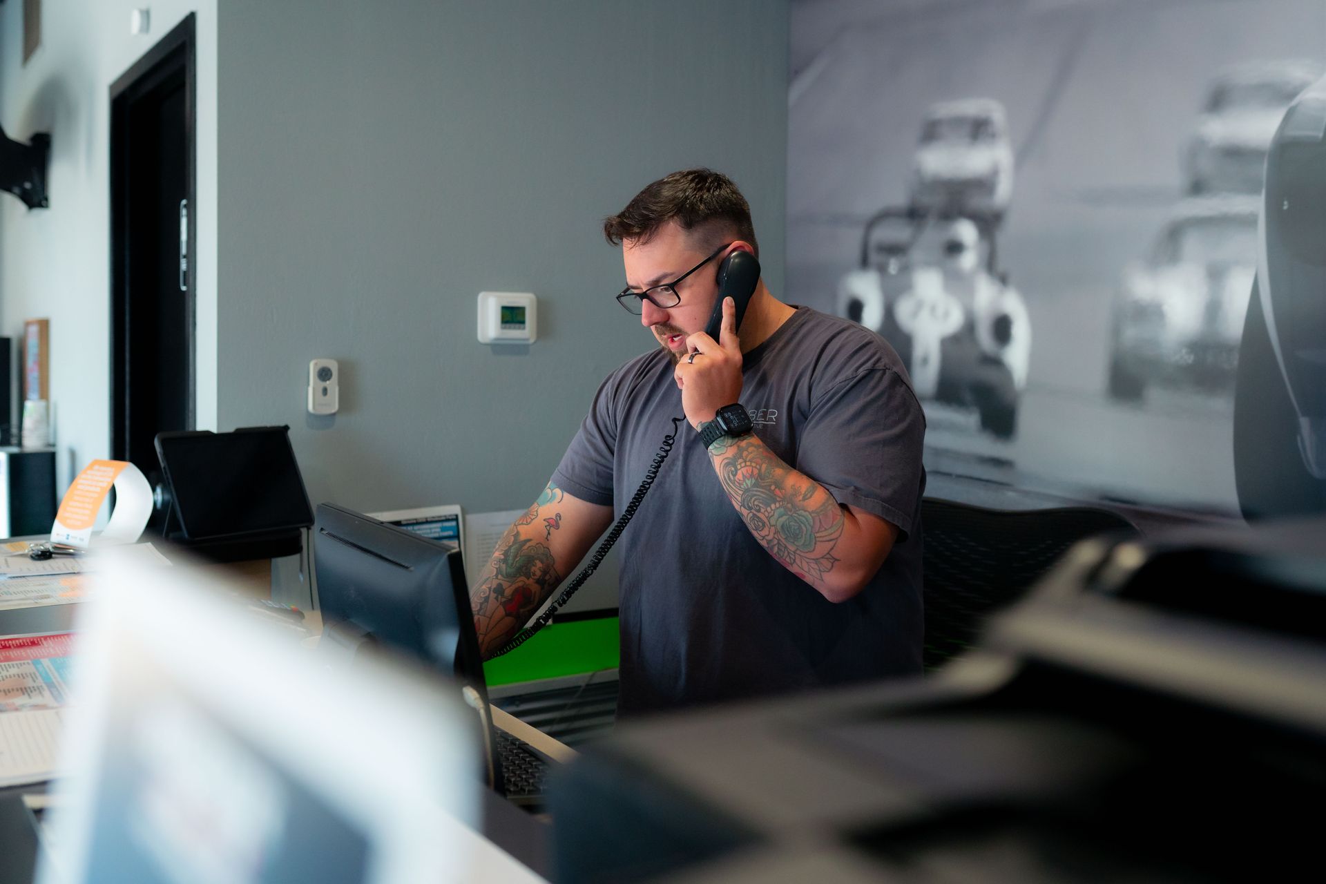 An employee standing behind the front desk holding a phone | Huber Automotive