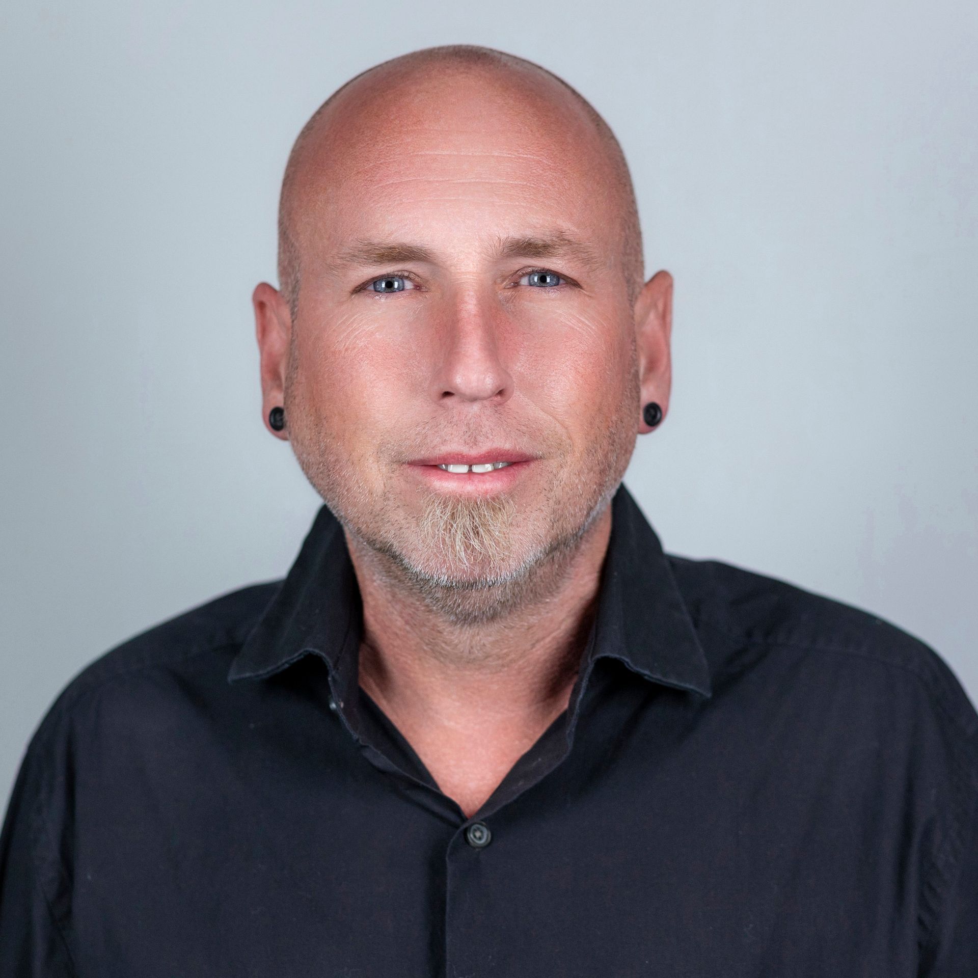 A woman wearing a black shirt and earrings is smiling for the camera.