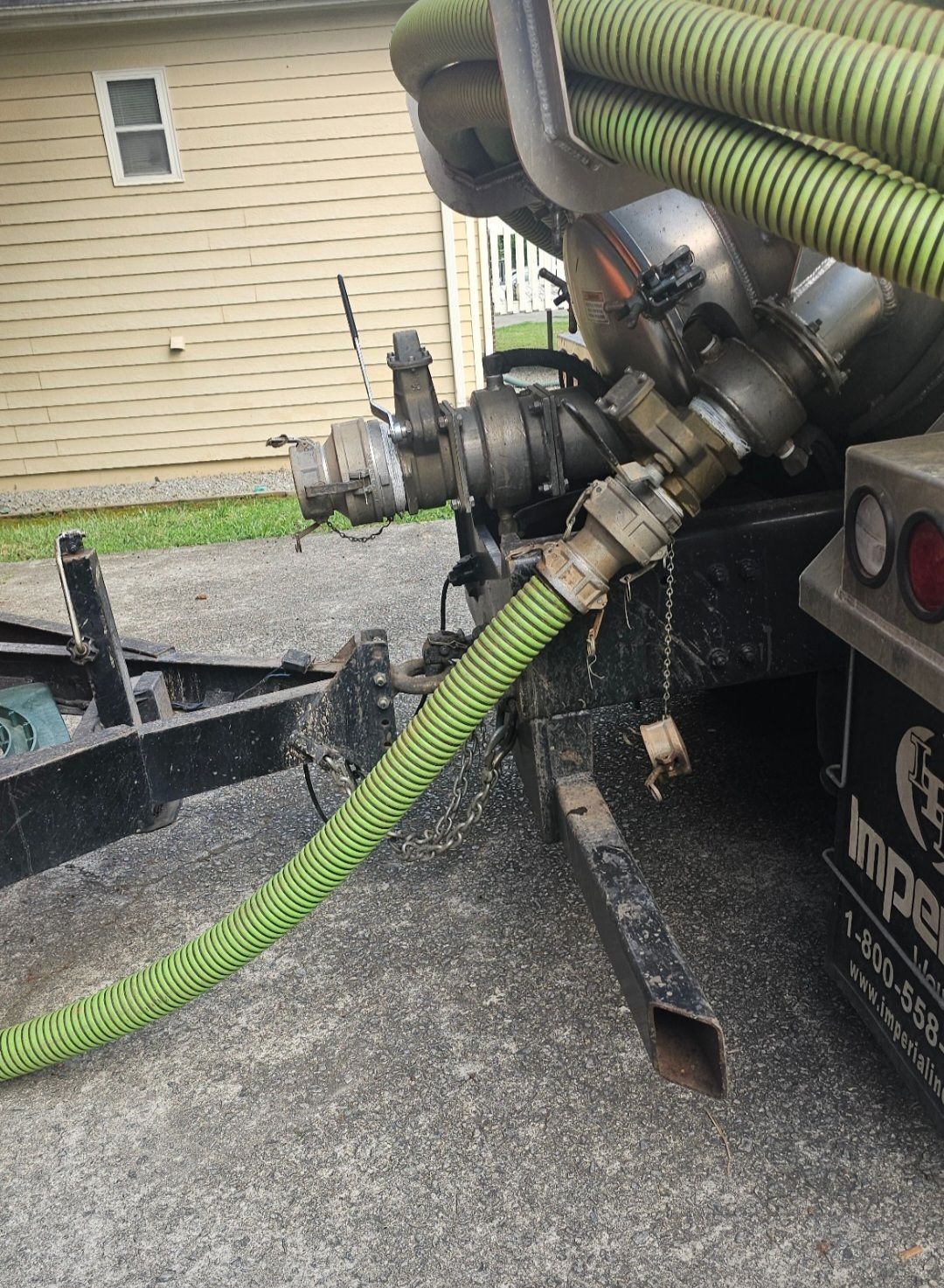 A green hose is attached to the back of a truck.