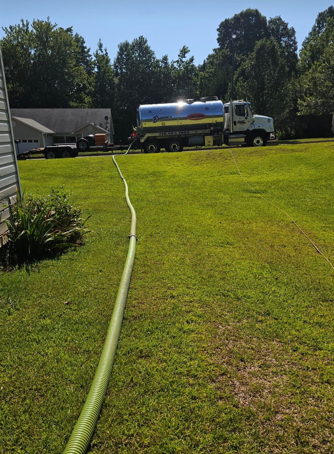 A hose is connected to a truck in a grassy field