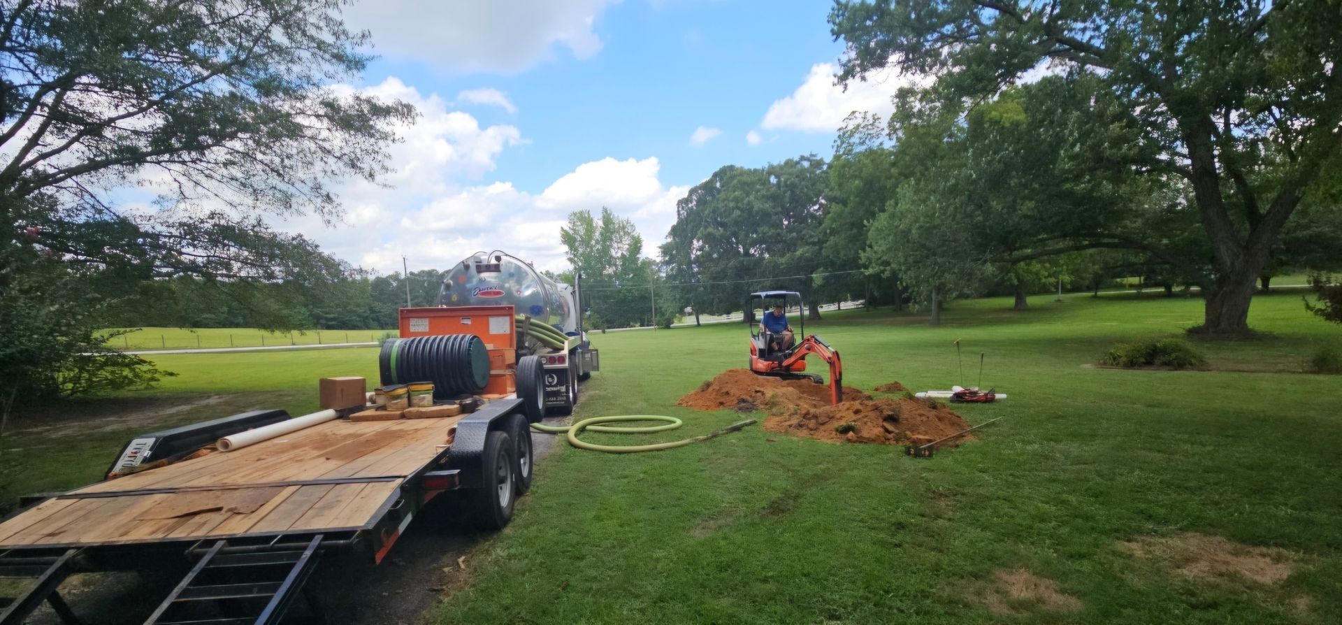 A trailer is parked in a grassy field next to a tractor.