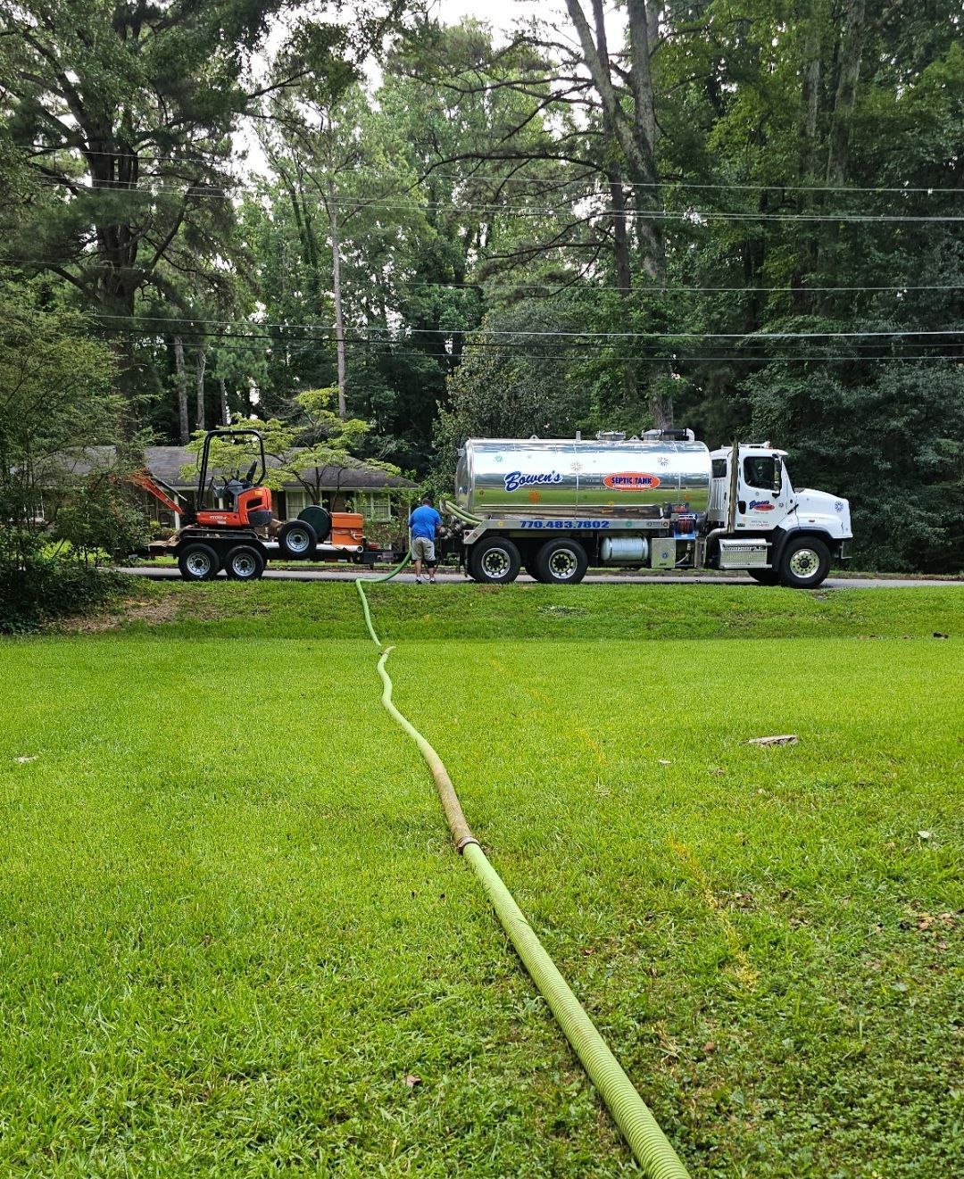 A hose is connected to a truck in a grassy field.