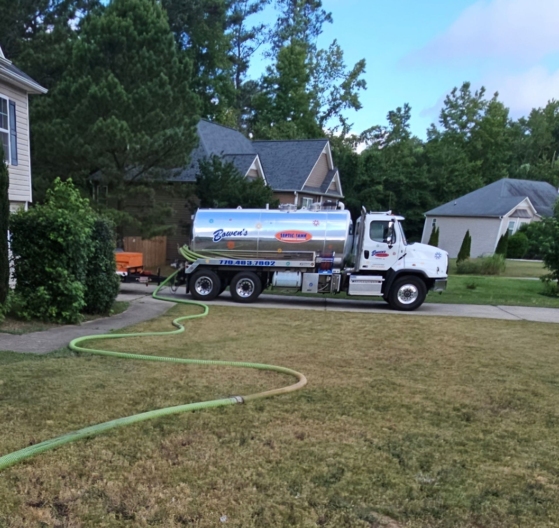 A silver tanker truck with a hose attached to it