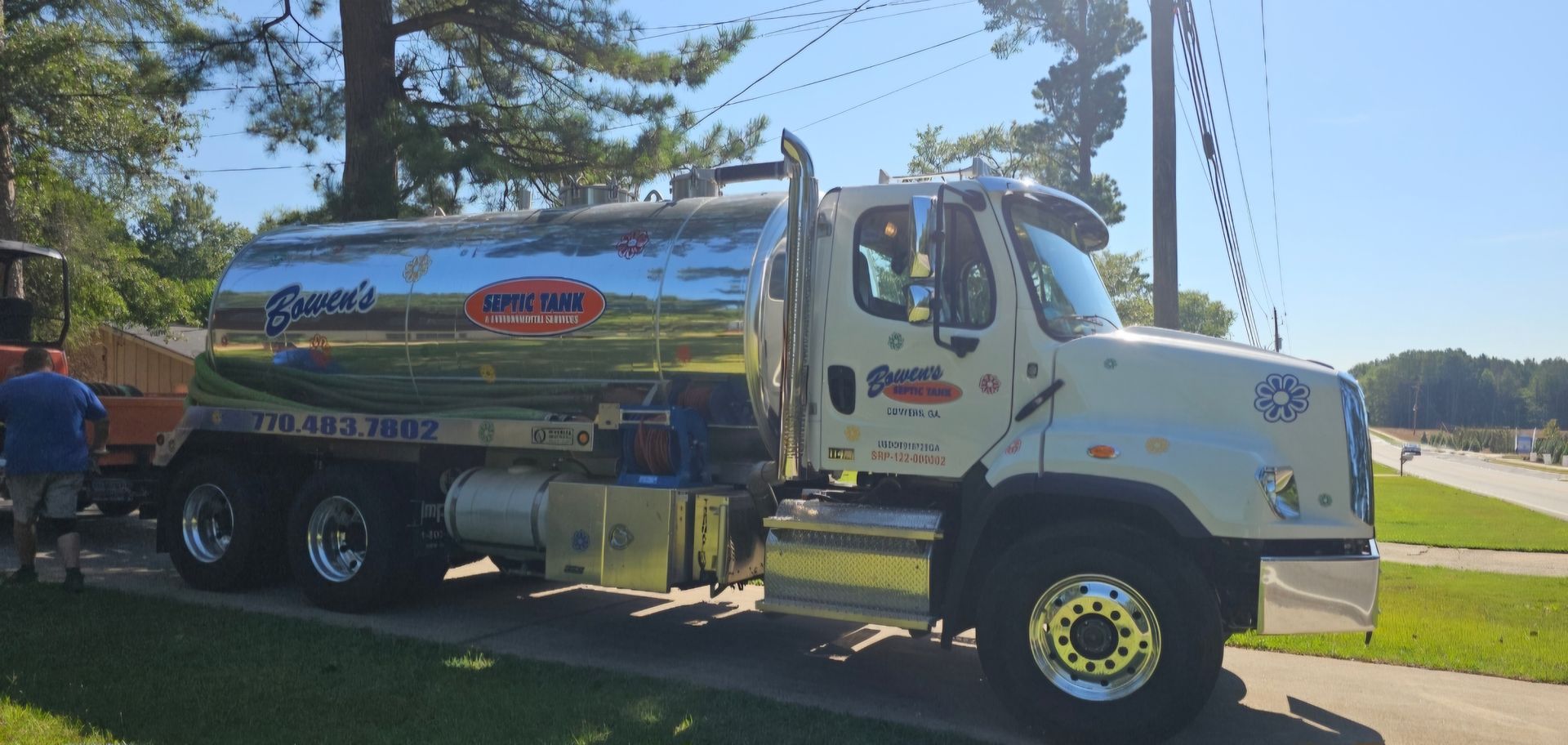A white tanker truck is parked on the side of the road.