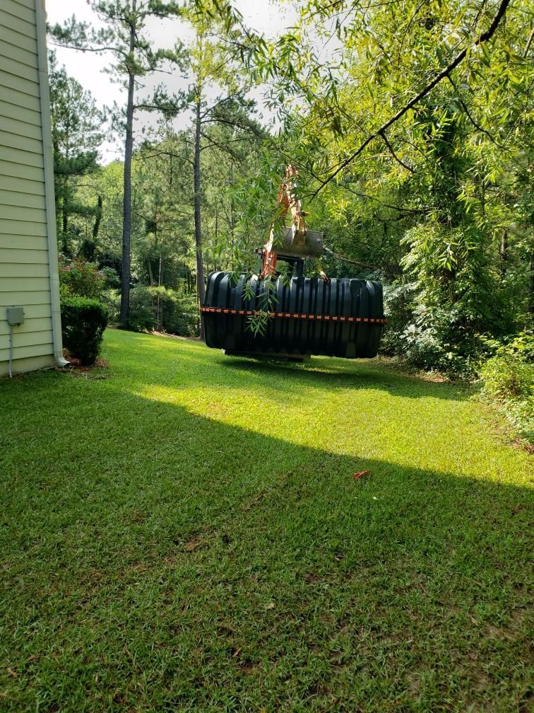 A Large Black Tank Is Sitting in The Grass in Front of A House.