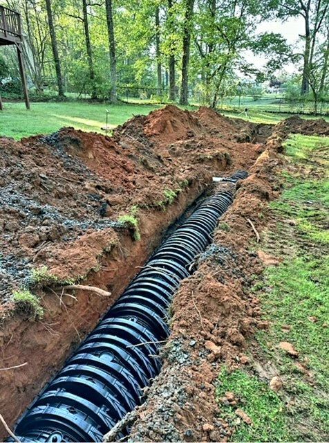 A Large Pipe Is Being Installed in The Dirt in A Yard.