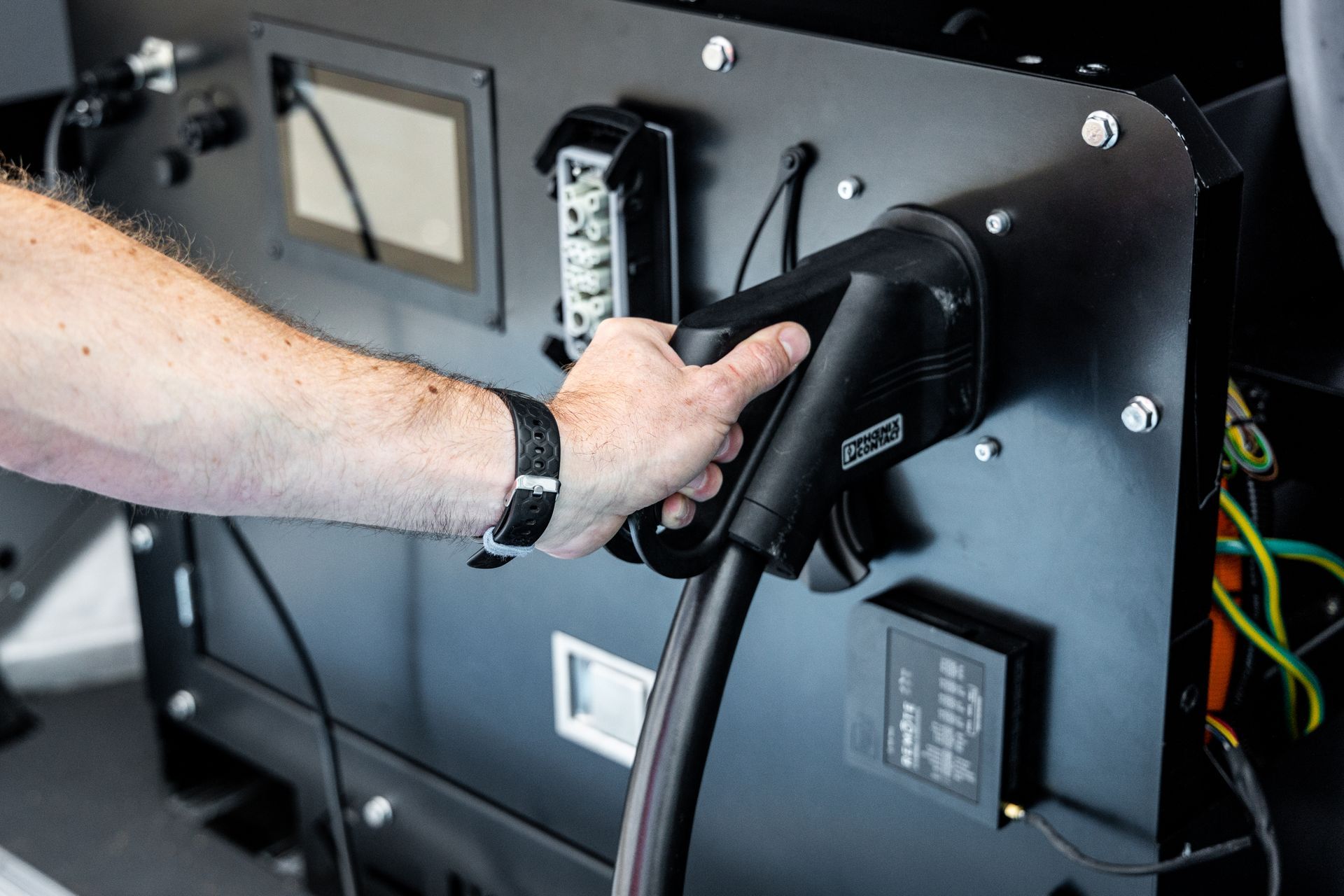 A person is plugging an electric vehicle into a charging station.