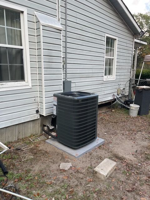 Air conditioner unit outside a light gray house.