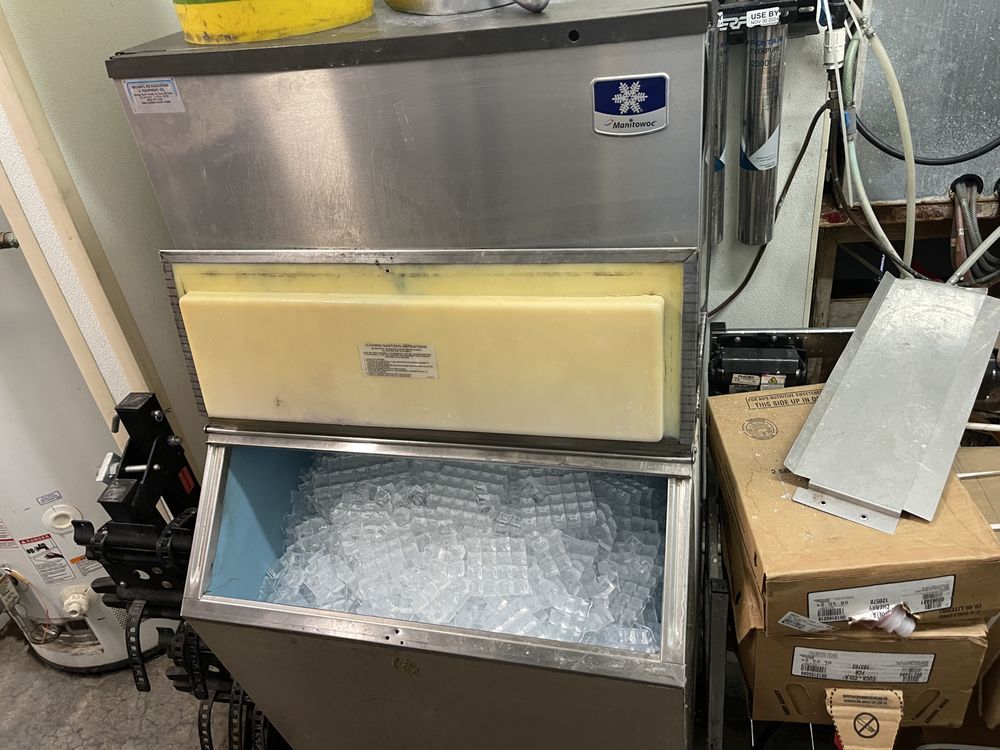 Stainless steel ice machine with open bin filled with ice.
