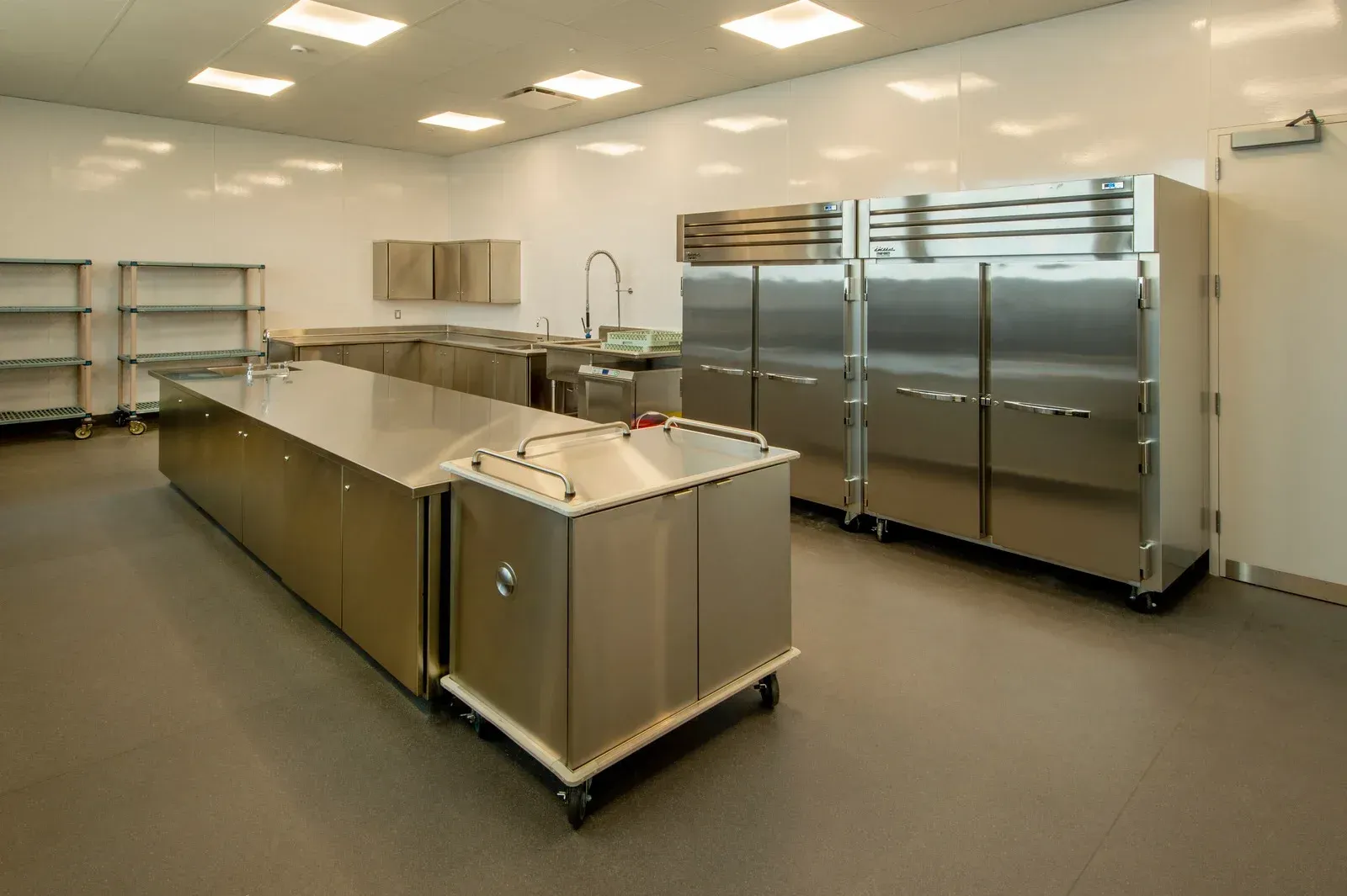 Commercial kitchen with stainless steel appliances, prep tables, and shelving.