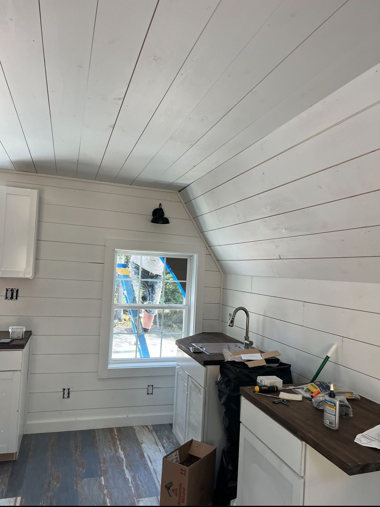 A kitchen with white cabinets , a sink , and a window.