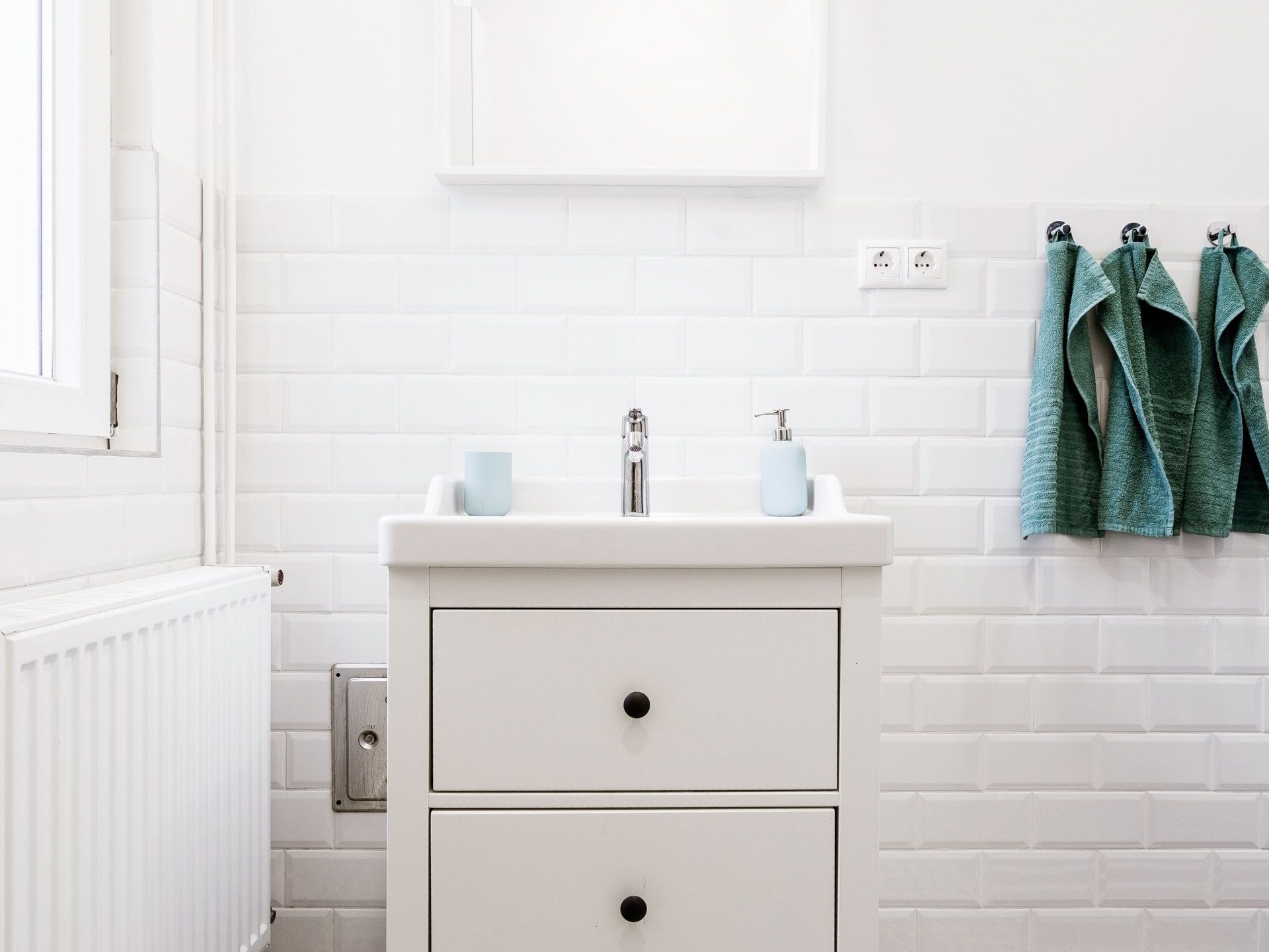 A bathroom with a sink , mirror and towels hanging on the wall.