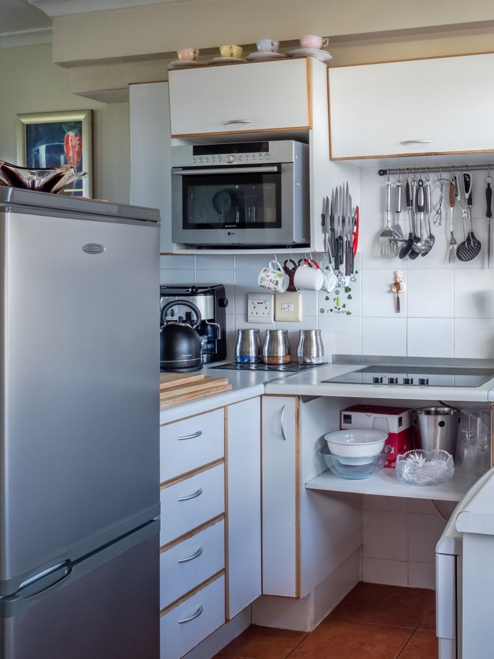 A kitchen with white cabinets , a stainless steel refrigerator , a sink , and a microwave.