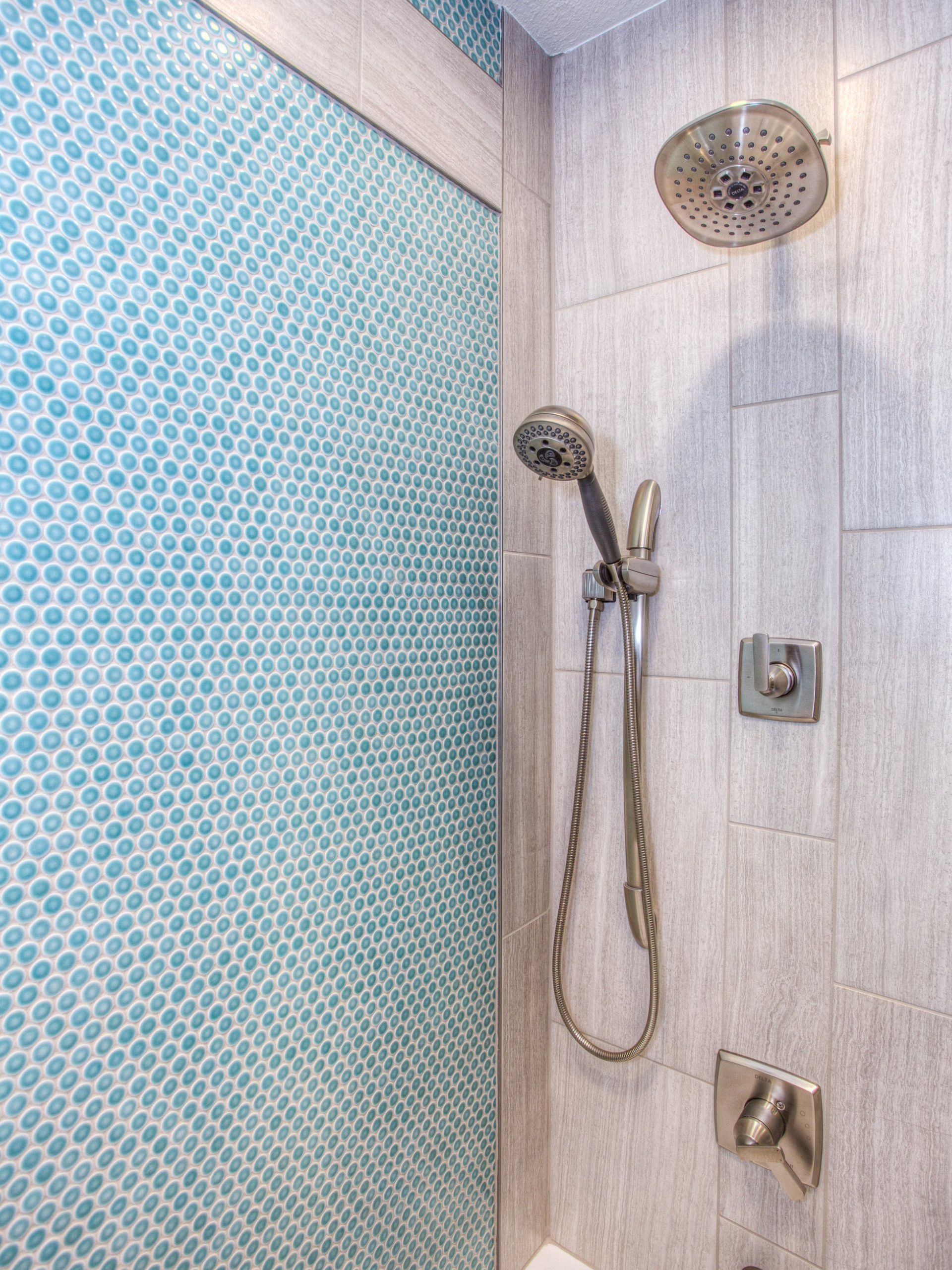 A shower with blue tiles and a shower head