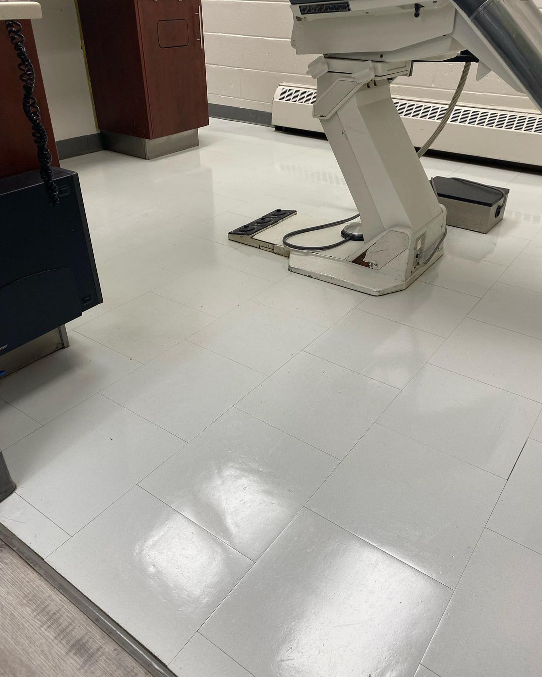 Un fauteuil dentaire est posé sur un sol carrelé blanc dans un cabinet dentaire.