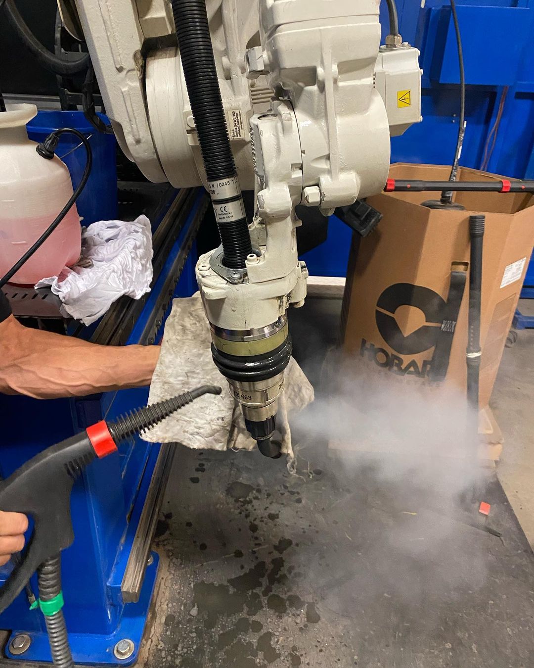 Une personne nettoie une machine avec un nettoyeur haute pression.