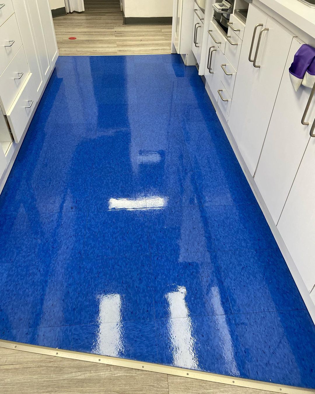 Une cuisine avec un sol bleu et des armoires blanches