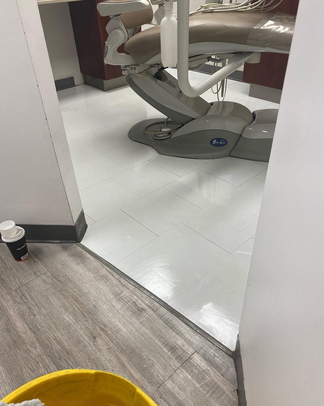 Un fauteuil dentaire est posé sur un plancher en bois dans un cabinet dentaire.