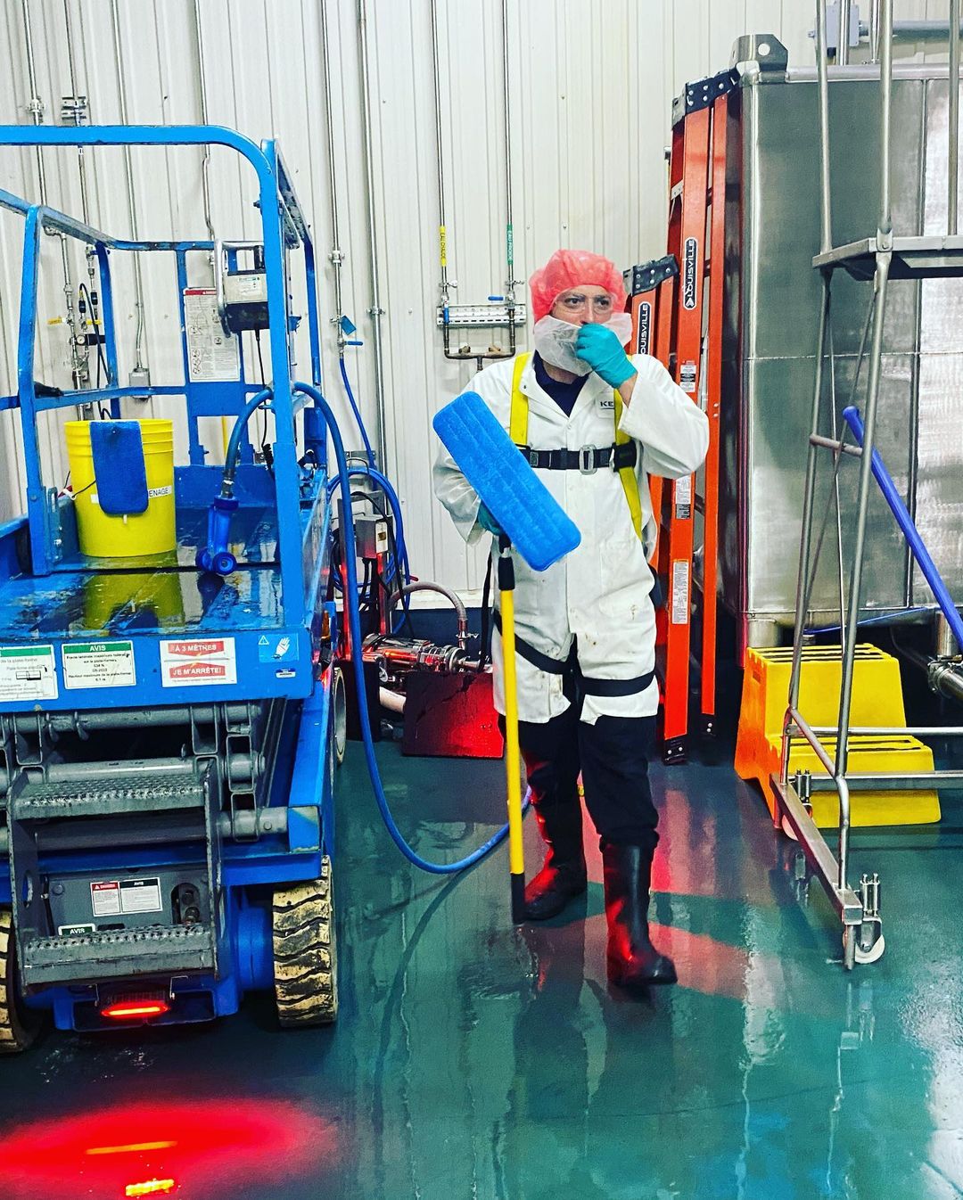 Un homme en tenue de protection pulvérise quelque chose dans une pièce