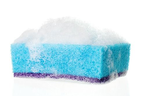 Une éponge bleue avec de la mousse dessus sur un fond blanc.