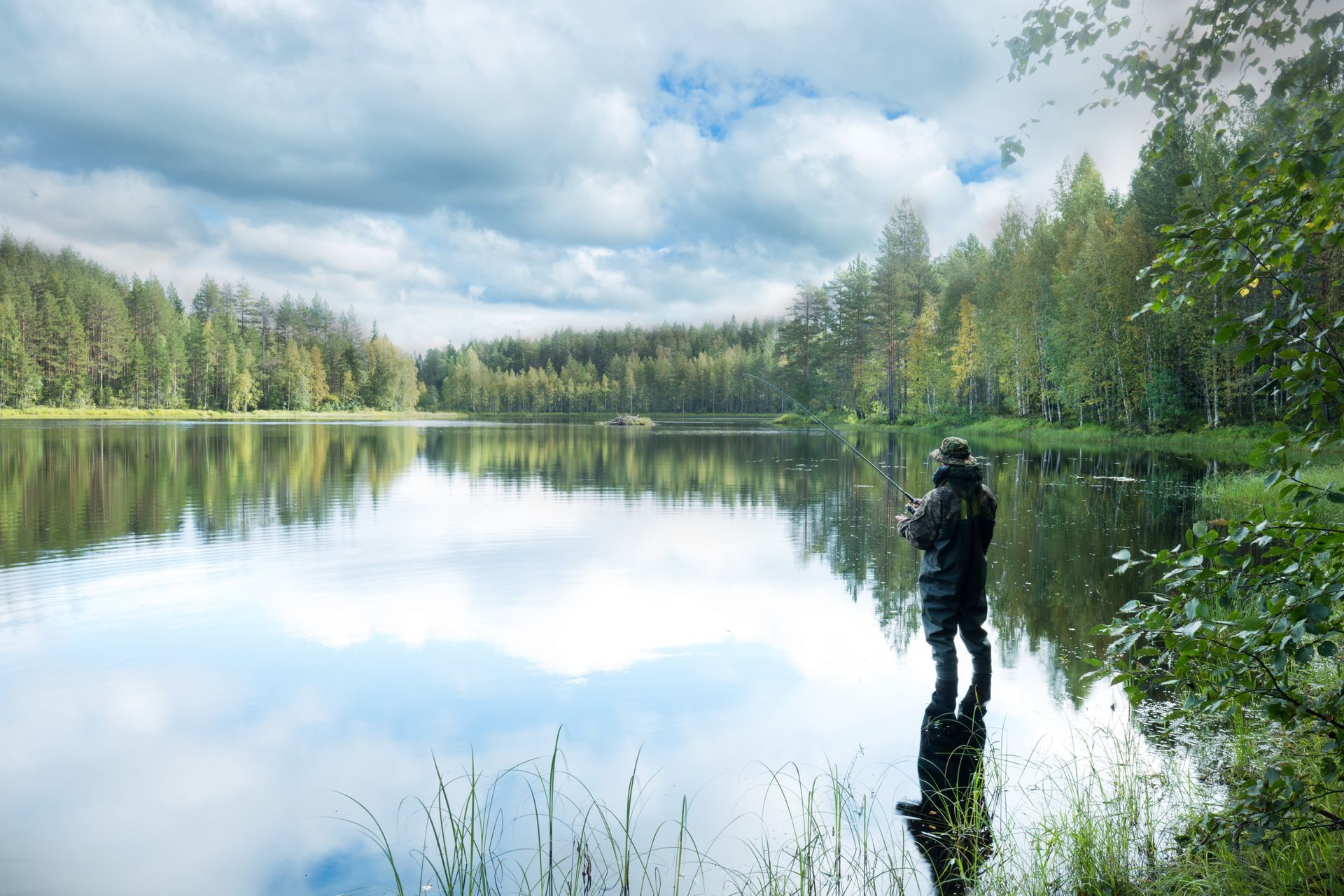 A man is standing on the shore of a lake.