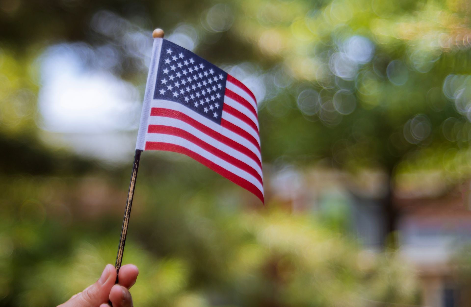 A person is holding a small american flag in their hand.