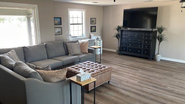 A person is holding a hamburger in their hands on a wooden table.