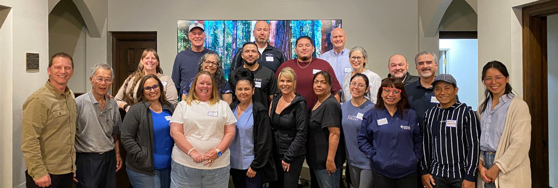 A group of people in a room, standing in front of a blue and white painting.