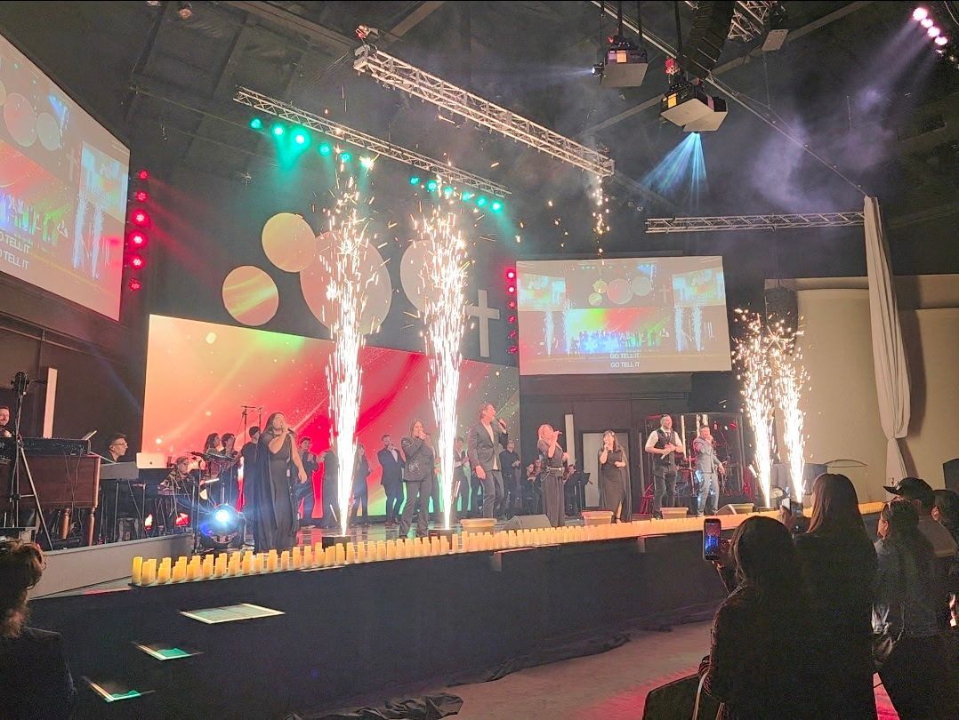 Stage performance with performers, pyrotechnics, lighting, and an audience.