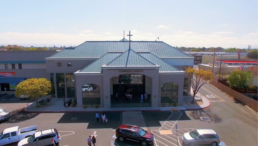 Compass Church of Salinas & Monterey County exterior with blue roof, cross, and parked cars on a sunny day.