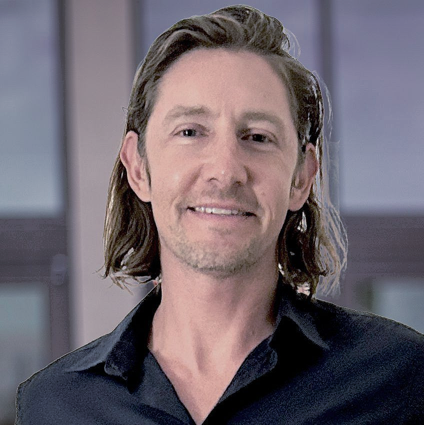 Man with long, dark hair, wearing a black shirt, smiling.