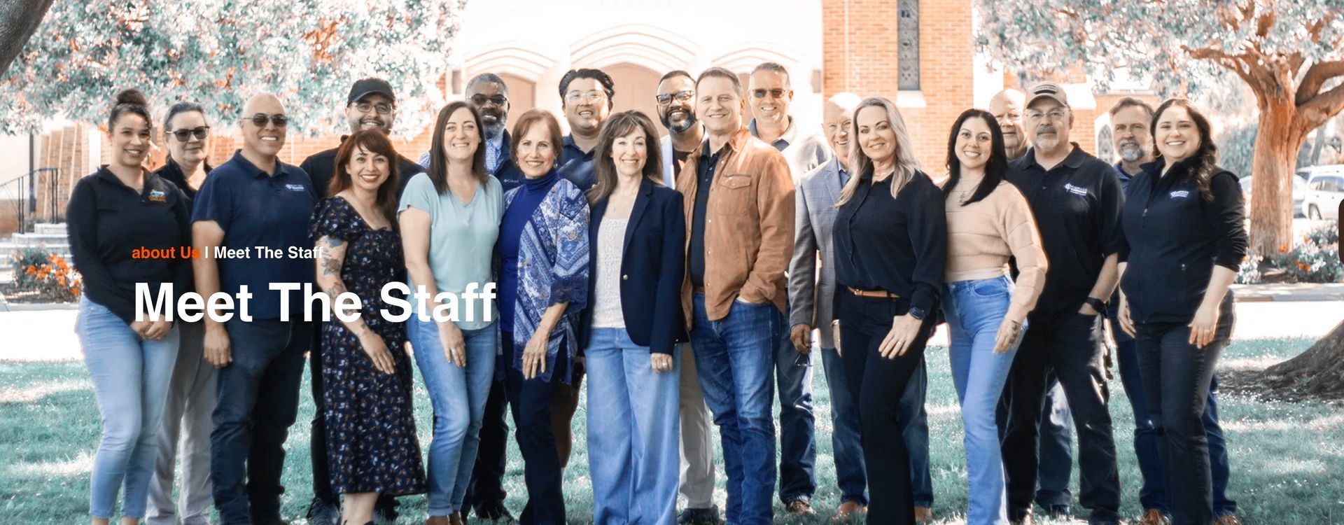 The staff of Compass Church is posing for a picture in a park.