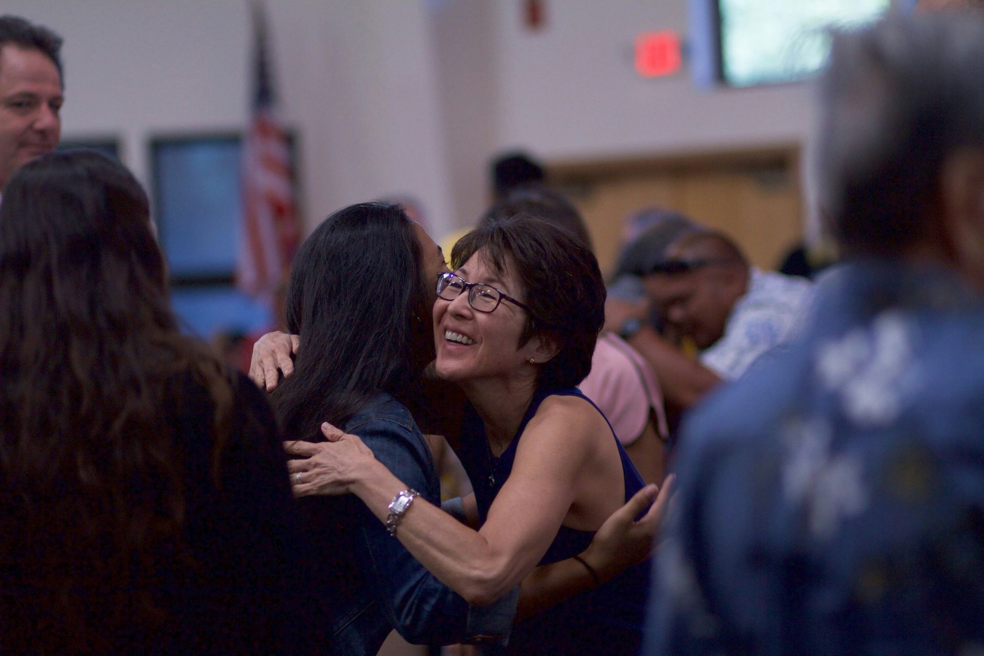 Group of diverse people at Compass Church, Monterey County, smiling in an indoor setting, some with arms around each other.