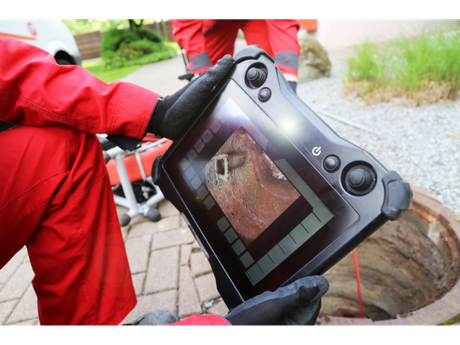 A man in red pants is holding a tablet in his hands