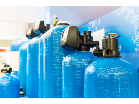 A row of blue water filters are lined up on a wall.