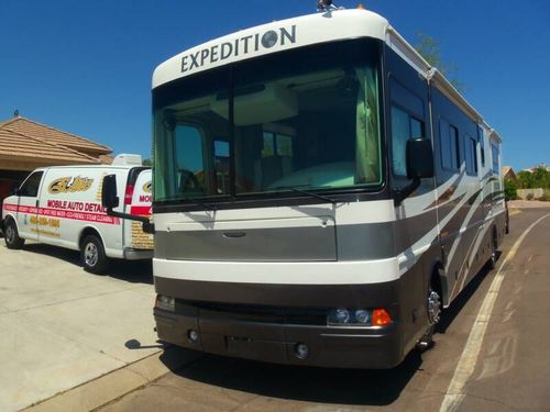 An expedition bus is parked next to a white van