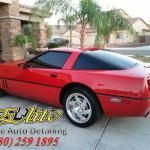 A red corvette is parked in a driveway in front of a house.