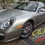 A silver porsche 911 is parked in a driveway.