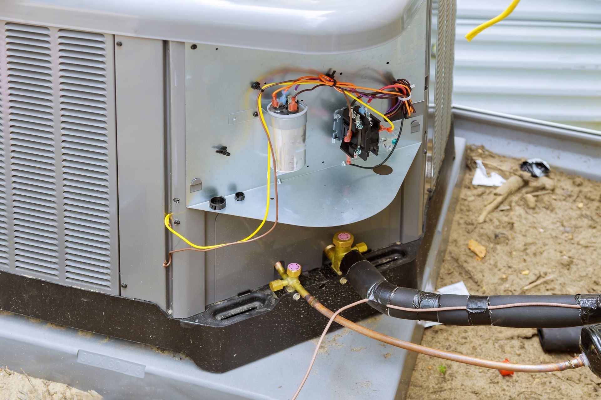 Open HVAC unit with exposed wiring and technician’s tools during repair outdoors