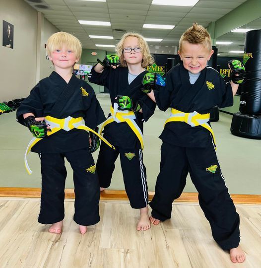three young boys wearing black karate uniforms with yellow belts