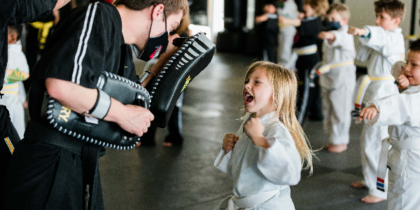 a young girl is practicing taekwondo in a gym .