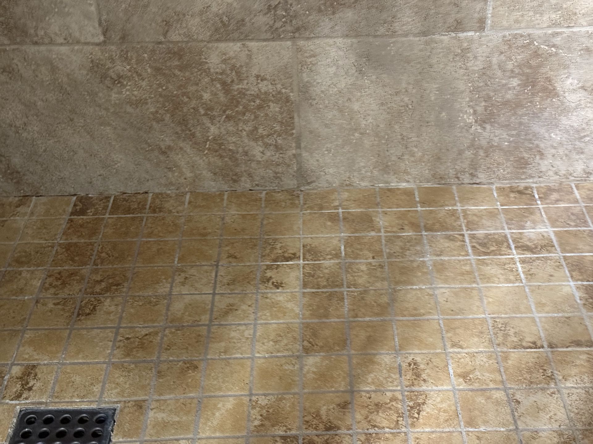 Shower interior with beige tile floor and walls.