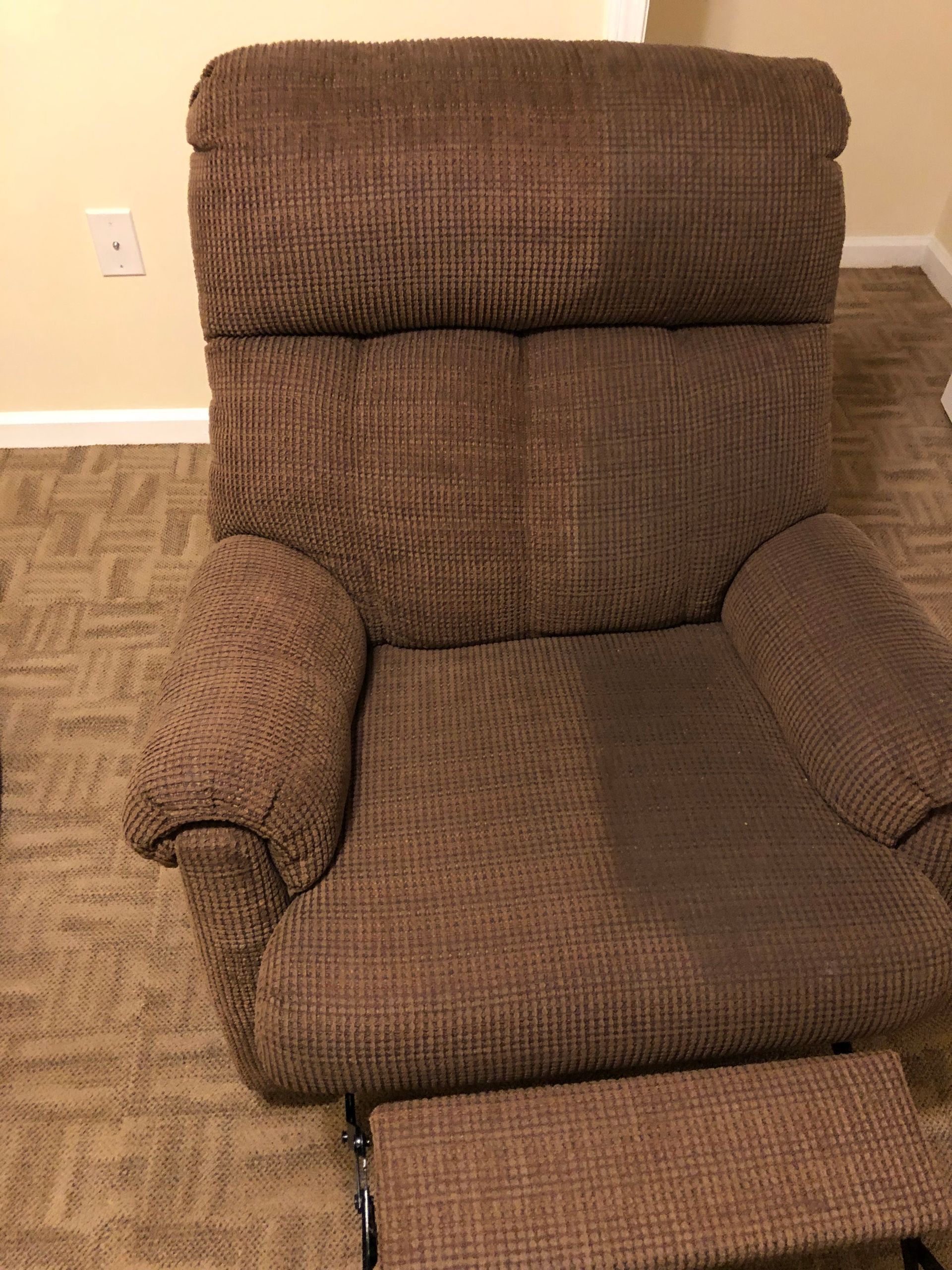 Brown upholstered recliner chair on a patterned carpet.