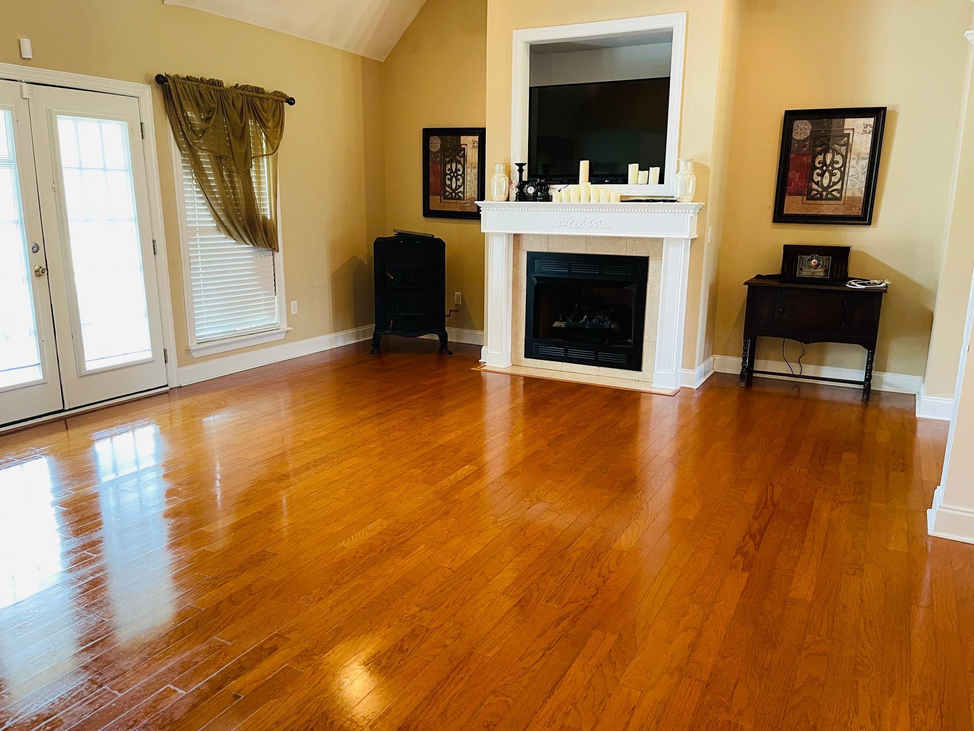 Bright living room with hardwood floors, fireplace, and french doors.