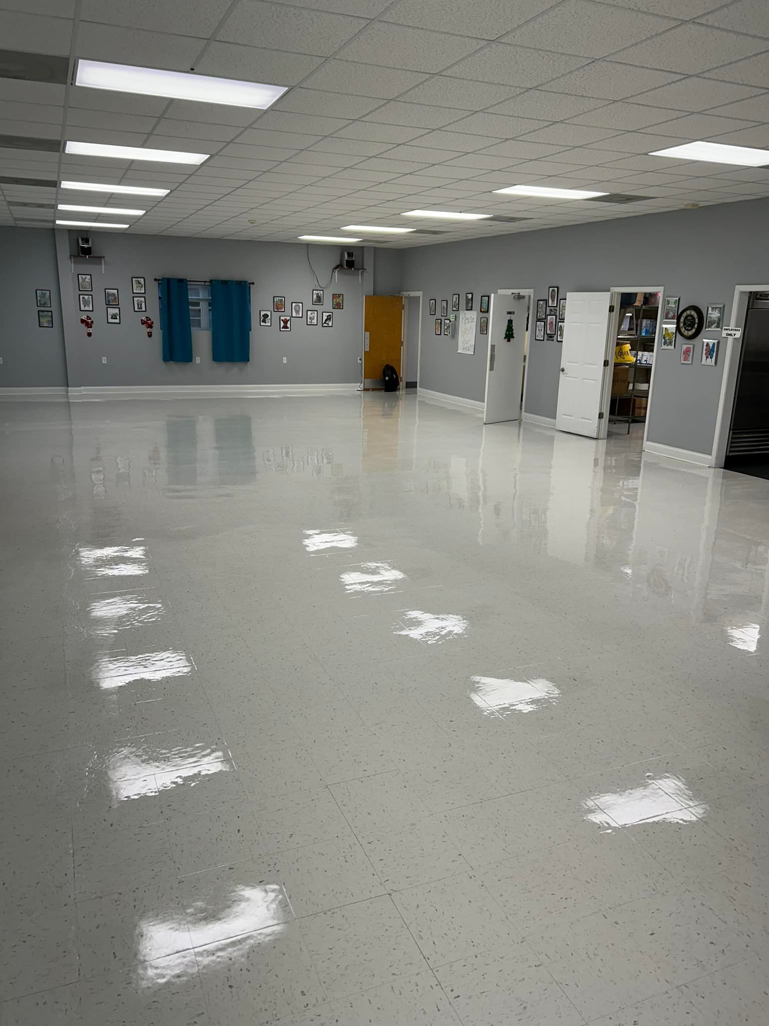 Empty dance studio with shiny, speckled floor, mirrors, and multiple doors.